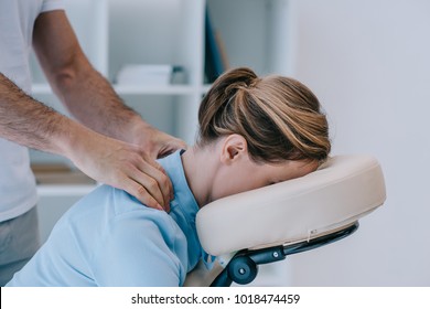 masseur doing shoulders massage for businesswoman in shirt