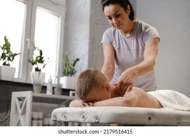 Masseur Gives The Child A Back Massage. Kids Massage Concept. Massage Therapist Giving 7 Year Old Boy Shoulder Massage. Physical Therapy