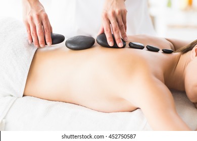 Masseur Giving Hot Stone Massage To Woman At Spa