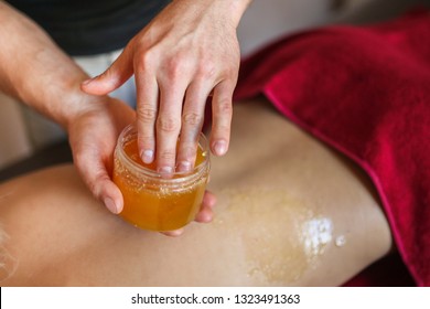 The masseur makes an anti-cellulite massage with honey to a beautiful girl . Medical treatments in the massage room - Powered by Shutterstock