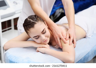 Masseur Man Doing Shoulder Girdle Massage To Attractive Young Woman