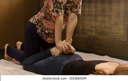 Masseur massaging back of female in spa resort, relaxed patient enjoys. Thai massage or Thai yoga massage treatment.