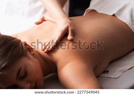 masseur massaging back and shoulder blades of young woman on massage table on white background. Concept of massage spa treatments. body relaxation procedures. Close-up