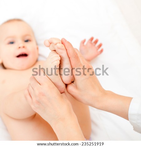 Masseur massaging little baby's feet, shallow focus