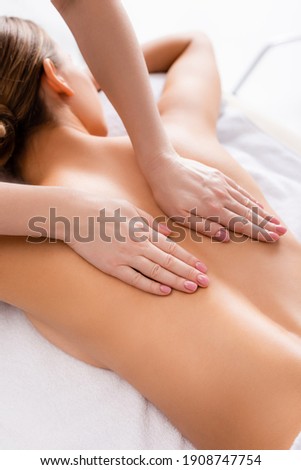 masseur massaging young client lying on massage table
