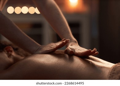 Masseuse applying hard pressure into sore muscles of female client