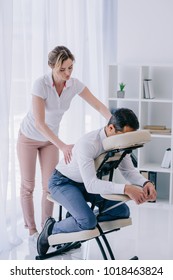 masseuse doing back massage for businessman at office