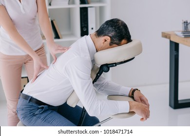 Masseuse Doing Back Massage On Seat At Office