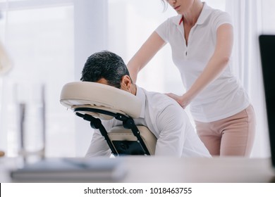 masseuse doing seated massage for businessman