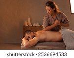 Masseuse gives a man a massage with her elbow in a romantic setting, Relaxing massage in a warm candlelit setting