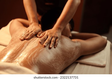 Masseuse hand applying salt scrub on back customer at cosmetology spa centre. Relaxation man customer get service skincare scrubbing massage with masseuse in spa salon. Selective focus.