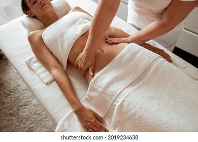 Masseuse hands massaging woman abdomen in spa salon - Powered by Shutterstock