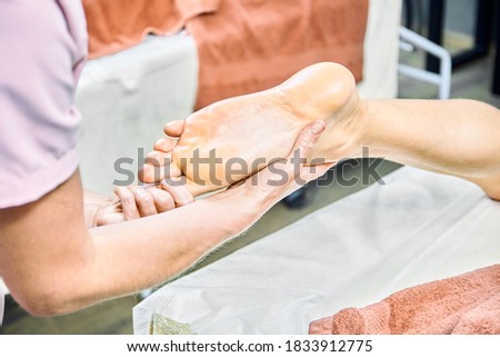 masseuse makes massage to the man's feet in the spa salon
