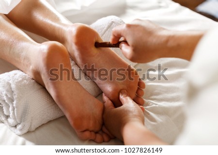 Masseuse massaging feet of person at massage salon