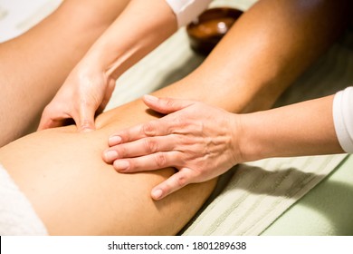 Masseuse woman hands giving a leg massage, finding a contracture, trigger point, a tight part in the muscle - Powered by Shutterstock