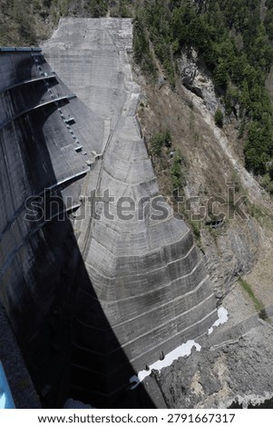 Massive architectural concrete structure of Kurobe Dam from above.