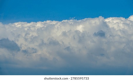 Massive dramatic cumulus clouds floating across a bright blue sky during daytime. This high-resolution nature photograph captures detailed cloud formations and peaceful atmospheric scenery, perfect for weather concepts, nature backgrounds, environmental themes, sky wallpapers, and outdoor stock photography.