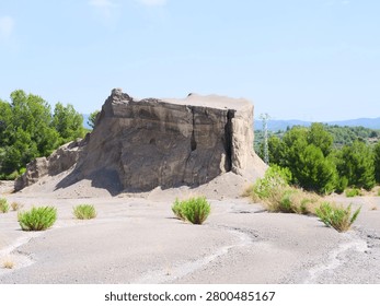 Massive eroded clay and soil formation standing in a dry desert landscape under a blue sky