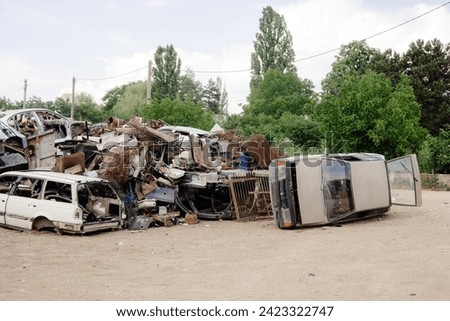 A massive heap of damaged cars in various states of disrepair, stacked high in a junkyard. These discarded vehicles await their turn for recycling and salvaging in the industrial recycling industry.