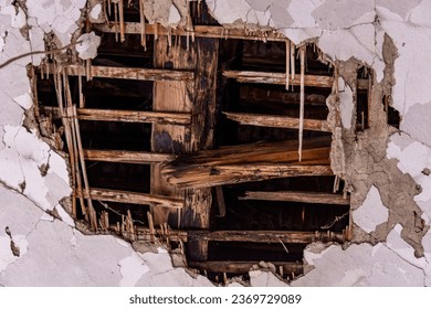 A massive hole in the ceiling revealing old, charred beams in an ancient house. Evokes the passage of time and the transience of aging materials