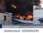 Massive large blaze fire in the city, blazing warehouse factory, storage building burning, firefighters team putting out the fire, firemen on duty, extinguish the fire, arson, burning house damage 