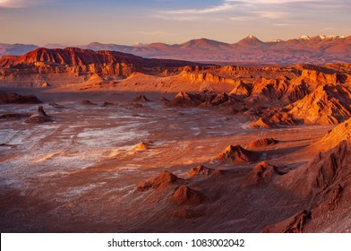 A Massive Moon Crater With Salt Deposit In The Middle Of Eerie Terrain At The Valle De Luna, Or Moon Valley, At San Pedro De Atacama. Sunset Light Casts Shadow On Mountains And Changes Its Colours.