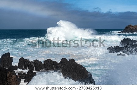 Massive ocean wave exploding against volcanic rocks.