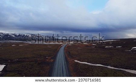 Massive roads between snowy mountains and frozen fields in iceland, drone shot of icelandic roadside with beautiful landscapes. Scandinavian scenic route with hills, winter scenery.