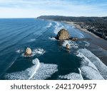 Massive sea stacks stand amid waves along Cannon Beach, Oregon. This scenic region, where forest meets the ocean, is known for its beautiful beaches, sea stacks, and tide pools.