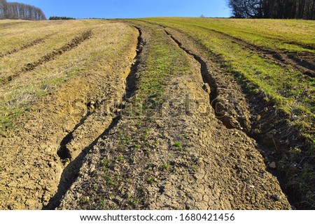 Massive soil erosion landscape field and road destruction by erosive process of water, environmental damage.