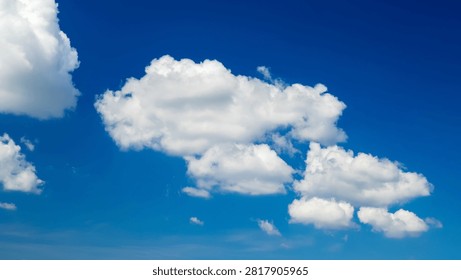 massive white cumulus cloud of complex shape occupies the center of the frame against deep blueness of the firmament on a sunny summer day creating a cool feeling