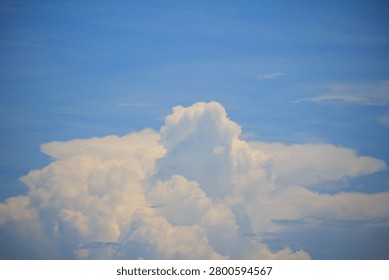 A massive, white cumulus cloud structure developing under a vast and clear blue sky