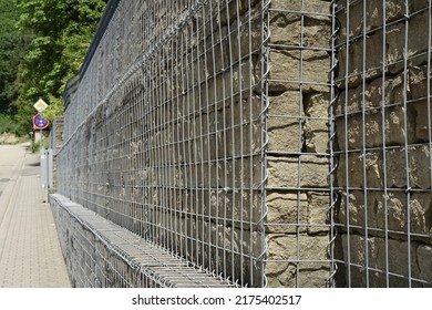 Massive yellow quartzite granite wall behind mesh wire, sunny spring day, concept: protection, defence
