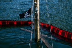 The Mast Of A Sunken Boat With A Pirate Flag Sticking Up From The Sea