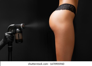 Master Applies Liquid Tan Spray For Professional Athlete Woman Using Airbrush In Beauty Salon.