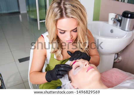 The master apply scrub on eyebrows with brush for prepare them to dyeing.