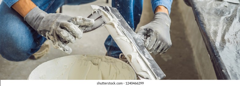 master is applying white putty on a wall and smearing by putty knife in a room of renovating house in daytime BANNER, long format