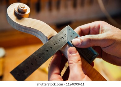 Master artisan luthier working on creation of a violin scroll. detailed work on wood with tools. Men's hands Measures the thickness of the scroll with meter . on the background of a workshop - Powered by Shutterstock