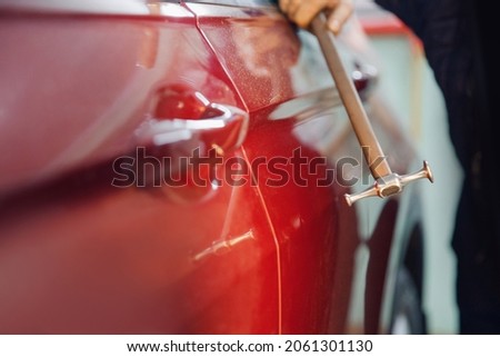 Master auto mechanic removal of dents defects without painting on car body on service station.