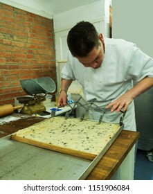 Master baker authentic kitchen making Lardy cake using cutter.