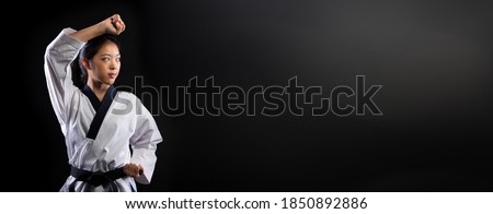 Master Black Belt TaeKwonDo Karate girl who is national athlete young teenager show traditional Fighting poses punch in sport uniform dress, black background isolated, motion blur on foots hands
