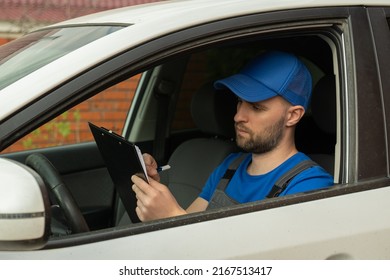Master in cap writes data about car details from dashboard sitting on driver seat in white car. Person sits in auto and writes on clipboard with pen