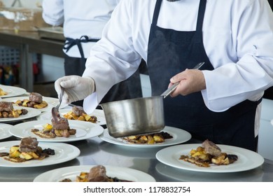 Master chef cooking Lamb with baked potatoes on restaurants kitchen. white dishes.