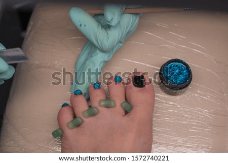 Master chiropody applying gel nail polish. Spa. Concept body care. Gel nail polish on the legs