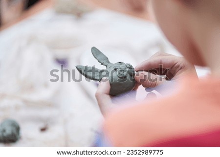 A master class for children on making toys from clay. A boy sculpts a figurine of an animal. Selective close-up focus with copy space. High quality photo
