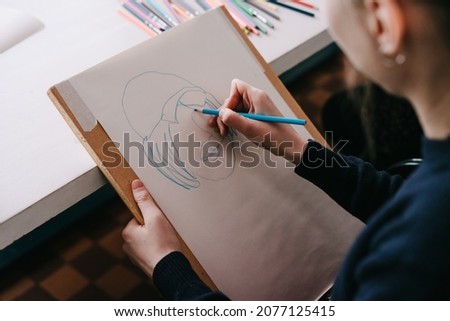 A master class in drawing portraits in the style of doodle. Drawing. Sketching with a colored pencil. The girl is in the process of drawing. Selective focus.