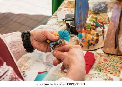 Master class on making handmade souvenirs. A woman makes a decorative doll-amulet.