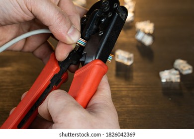 The master clears the cable from the insulation and crimps the utp cable with the tool. - Shutterstock ID 1826042369