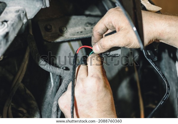 The master connects the wires under the hood of the\
car and insulates them. The concept of repairing the electrics of\
the car. An electrician is engaged in connecting the wires of the\
car.