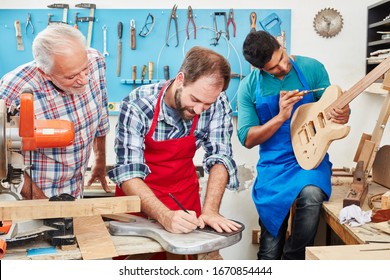 Master controls apprentice during training in workshop from the guitar maker - Powered by Shutterstock